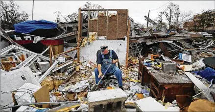  ?? DAVID GOLDMAN / ASSOCIATED PRESS ?? Patrick Muth sifts through debris in January in what used to be his office of his fifth-generation plumbing business he continues to operate in Panama City, Fla. “You have two options,” said Muth. “You can lay down and cry or you can keep marching.”