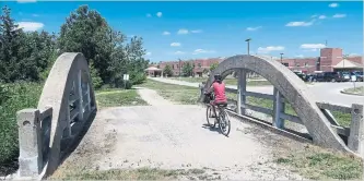  ?? PATRICK BRENNAN PHOTOS, SPECIAL TO THE TORONTO STAR ?? A biker crosses a bowstring bridge moved 20 kilometres to be part of the Elora Cataract Trailway. At right, the grave of Charles Mattaini, an Italian immigrant whose bridge design was widely used in southweste­rn Ontario.