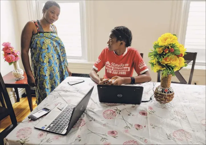 ?? Photos by Paul Buckowski / Albany Times Union ?? Sifa Eca, left, talks with her daughter, Ungwa Mnyomoelwa, a sophomore at Albany High School, as she works on her remote learning at their home in Albany,