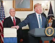  ?? PABLO MARTINEZ MONSIVAIS/AP PHOTO ?? President Donald Trump reaches to touch a copy of the $1.3 trillion spending bill as he speaks in the Diplomatic Room of the White House in Washington on Friday. Vice President Mike Pence looks on.