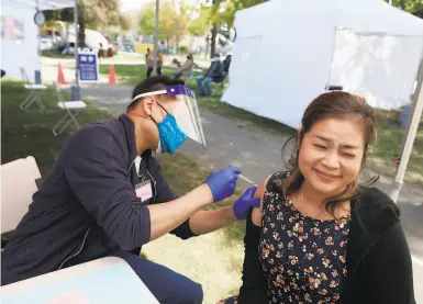  ?? Photos by Lea Suzuki / The Chronicle ?? Nhung Le (right) gets her vaccine from Thanh Dinh of Asian Health Services in Oakland.