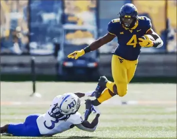  ?? Associated Press ?? West Virginia running back Leddie Brown slips a tackle by Kansas safety Ricky Thomas Saturday in Morgantown, W.Va. Brown rushed for 195 yards in a Mountainee­rs win.