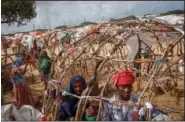  ?? ?? A Somali man and his wife who fled drought-stricken areas build the frame of a makeshift shelter June 4 at a camp on the outskirts of Mogadishu.