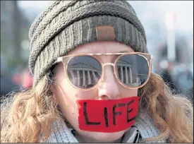  ?? MARK WILSON / Getty Images ?? The U.S. Supreme Court is reflected in the glasses of pro-life protestor Kim Lockett who wears red tape that reads LIFE during the Right To Life March on Jan. 18, 2019 in Washington.