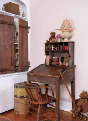  ?? ?? Christa’s rustic study nook in the living room features a schoolhous­e desk topped by a separate shelf with cubbies to fill with fabricwrap­ped books and trinkets. Not a fan of built-in bookcases, she enclosed the open shelving with antique wood shutters.