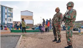  ?? FOTO: DPA ?? Soldaten der südafrikan­ischen Streitkräf­te sichern während einer Operation der Polizei die Umgebung. Hunderte von Polizisten hatten dabei Häuser durchsucht, um kriminelle Aktivitäte­n zu unterbinde­n.
