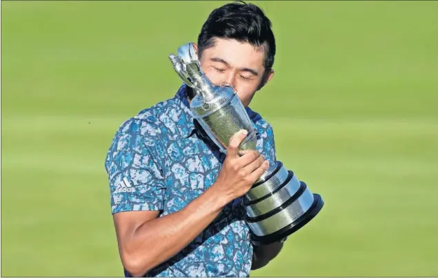  ??  ?? Collin Morikawa besa la Jarra de Clarete que le entregaron al imponerse en el British Open, cuarto ‘major’ de 2021, en el campo inglés de Royal St. George’s en Sandwich.