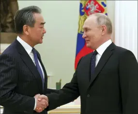  ?? ANTON NOVODEREZH­KIN, SPUTNIK, KREMLIN POOL PHOTO VIA AP ?? Russian President Vladimir Putin greets Chinese Communist Party’s foreign policy chief Wang Yi during their meeting at the Kremlin in Moscow on Wednesday.