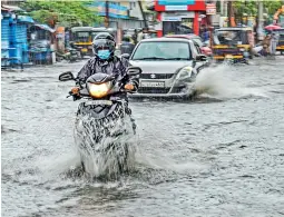  ?? — PTI ?? Commuters wade through a waterlogge­d road during monsoon rains, in Kochi on Monday.