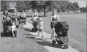  ??  ?? Above, Moms push their strollers to another activity at a FIT4Moms Stroller Strides class in August at Chancellor’s Run Regional Park in Great Mills. Below, Christina Stover of Great Mills does sit-ups with her 10-month-old daughter, Naomi.