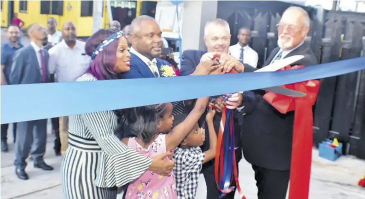  ??  ?? NK Customer Solutions principal partner Roger Williamson second left, is joined by (from left) his wife Sandra, his business partners Randy Tustin and Ron Esten, and his children Keirean and Nolan, in cutting a ribbon to officially declare the Annotto Bay, St Mary business process outsourcin­g company open last week Thursday.