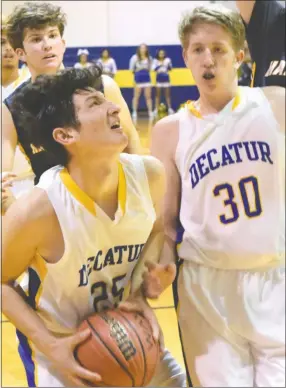  ?? Westside Eagle Observer/MIKE ECKELS ?? After pulling down a rebound, Kevin Garcia (Decatur 25) fights to put up a layup as his teammate Ryan Ross (30) tries to back out of his way during the Decatur-Haas Hall conference basketball game in Decatur Dec. 4.