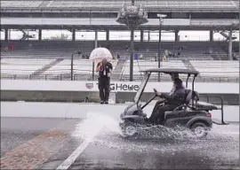  ?? Darron Cummings Associated Press ?? A CART swishes through the start-finish line at Indianapol­is Motor Speedway after rain canceled the first day of qualifying runs for next weekend’s race.