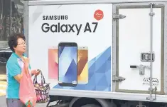 ??  ?? A woman walks past advertisin­g showing the Samsung Galaxy A7 smartphone on the street in Seoul. Sprawling South Korean conglomera­te Samsung Electronic­s has recovered from a humiliatin­g recall fiasco and the arrest of its de facto leader with remarkable...