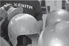  ??  ?? Reconditio­ning and recertifyi­ng helmets is a crucial step in the helmet production process. A helmet production logjam could threaten the start of the season for high school and youth programs.