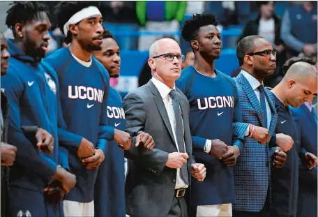  ?? JESSICA HILL/AP PHOTO ?? UConn coach Dan Hurley locks arms with his players during the national anthem prior to Sunday’s game against Arizona at the XL Center in Hartford. Hurley, a New Jersey native, will bring his Huskies to the Garden State for the first time today to face No. 11 Florida State at the Prudential Center in Newark, N.J.