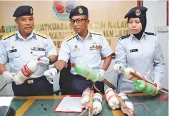  ??  ?? Mohd Zubil (centre) with Adam (left) and an MMEA officer showing the modified explosives that were seized from the suspects.