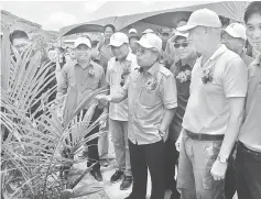  ??  ?? Masing takes a closer look at an oil palm seedling after officiatin­g at the launch. He is flanked by Ugak on his right and Kuo Hea. Nyabong is behind Masing.