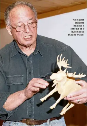  ??  ?? The expert sculptor holding a carving of a bull moose that he made.