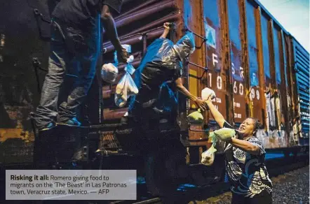  ?? — AFP ?? Risking it all: Romero giving food to migrants on the ‘ The Beast’ in Las Patronas town, Veracruz state, Mexico.