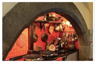  ??  ?? Top: Jill and Farquhar in the castle kitchen with dog Abby. Middle: One of Gerald’s bronze head sculptures. Bottom: The Aga is cleverly recessed into an arched stone alcove while scarlet metro tiles add a splash of colour.