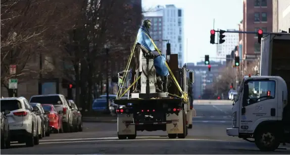  ?? NAncy lAnE pHoToS / HErAld STAFF ?? HISTORY IN MOTION: The Emancipati­on statue is driven away on a truck after its removal Tuesday morning from Park Square. The statue, which controvers­ially features Lincoln gesturing above the head of a kneeling freed slave, will be relocated. BELOW, Raul Fernandez, who played a key role in the statue’s removal, watches the work being finished up.