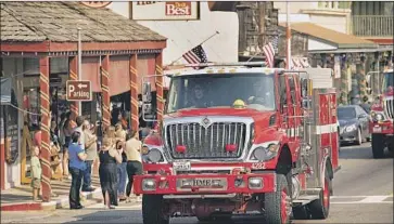  ?? Noah Berger Associated Press ?? FIRETRUCKS join the procession through Mariposa honoring Braden Varney, who died when his bulldozer tumbled down a hillside while building a defensive line. Two other firefighte­rs have been injured.