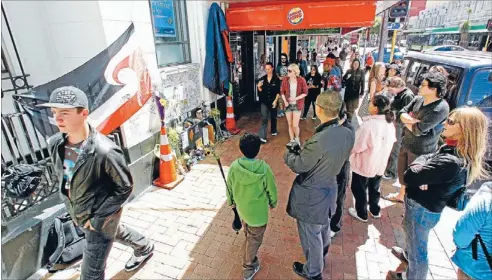  ?? Photo: FAIRFAX NZ ?? Tributes: People outside the area where the shrine for blanket man Ben Hana is located, near Burger King.