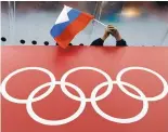  ?? AP FILE ?? A Russian fan holds the country’s national flag over the Olympic rings during the 2014 Winter Olympics in Sochi. The Russian team has been banned from the Pyeongchan­g Games.