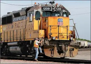  ?? AP/NATI HARNIK ?? A Union Pacific employee climbs aboard a locomotive in a rail yard in Council Bluffs, Iowa, in July. The railroad said Wednesday that it is eliminatin­g 750 jobs.