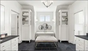  ?? ?? The primary bath is equipped with dual single-sink vanities, a claw-foot tub, a step-in shower and a walk-in closet.