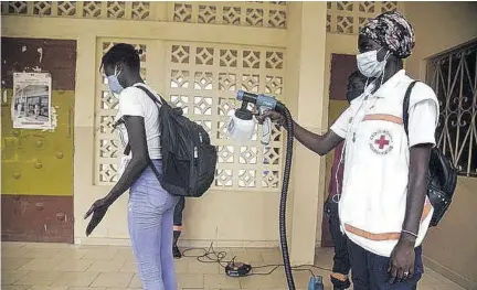 ?? (photo: afp) ?? A Red Cross worker sprays a student with disinfecta­nt at the entrance of a school in Dakar, Senegal, in 2020. Senegal placed second on Foreign Policy magazine’s list of 36 countries for their handling of COVID-19.
