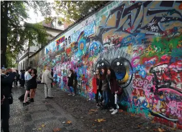  ??  ?? THIS PAGE: Tourists flock to the John Lennon Peace Wall, often spray painting their grafitti art and peaceful prose.OPPOSITE PAGE: Art Nouveau stained-glass window created by Czech painter Alfons Mucha in the St. Vitus Cathedral at Prague Castle.