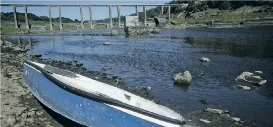  ?? Foto: dpa ?? Trockenhei­t in Galicien: Ein Boot ruht am Ufer des Río Miño, im Hintergrun­d sind die Ruinen des alten Portomarin zu sehen.