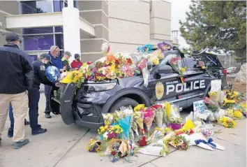  ?? DAVID ZALUBOWSKI/AP ?? Mourners leave flowers Tuesday on a patrol vehicle parked outside the Boulder Police Department in honor of Officer Eric Talley, who was killed after responding to a call reporting a gunman in a King Soopers grocery store Monday.