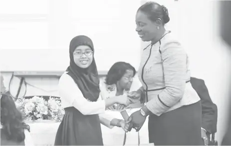  ??  ?? Top student, Naila Rahaman being congratula­ted yesterday by Minister of Education Nicolette Henry. (Department of Public Informatio­n photo)