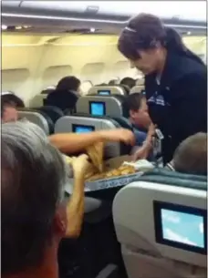  ?? AP PHOTO/LOGAN MARIE TORRES/FILE ?? A flight attendant passes out pizza to passengers aboard a Denverboun­d flight diverted to Cheyenne, Wyoming.