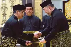  ??  ?? YANG di-Pertuan Agong menyerahka­n Surat Cara Pelantikan sebagai Menteri Hal Ehwal Ekonomi kepada Azmin.