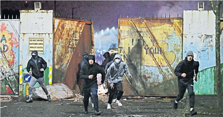  ??  ?? Above, rioters face up outside the peace wall that divides east and west Belfast. Left, fires break out in the street, while, right, a city commuter bus is torched and left to burn on the Shankill Road