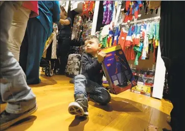  ?? Francine Orr Los Angeles Times ?? WHILE OTHERS look for Black Friday deals at the Disney Store at the Citadel in L.A., Adrian Leal, 3, is content with a Spider-Man toy. Having a budget — and updating it — helps keep expenses under control.