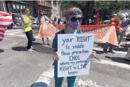  ?? MICHAEL DWYER/ASSOCIATED PRESS ?? A counterpro­tester holds a sign across the street from a rally calling for the lifting of government restrictio­ns outside the Massachuse­tts Capitol in Boston on Saturday.