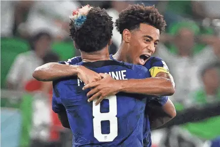  ?? PATRICK T. FALLON/AFP VIA GETTY IMAGES ?? Weston McKennie and Tyler Adams celebrate the USMNT’s first goal against Iran on Tuesday in their group stage finale at Al-Thumama Stadium in Doha, Qatar.