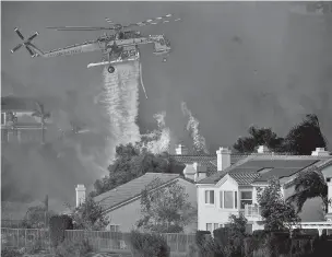  ?? NOAH BERGER/ASSOCIATED PRESS ?? A helicopter drops water Friday while battling the Saddleridg­e Fire in Porter Ranch, Calif.