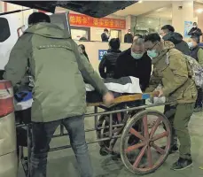  ?? FOTO: NOEL CELIS/AFP ?? Bestattung­sarbeiter legen eine Leiche auf einen Karren, um sie in einem Krematoriu­m in der chinesisch­en Stadt Chongqing einzuäsche­rn.