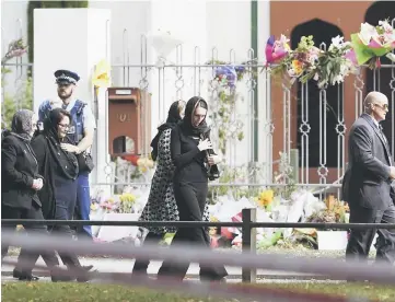  ??  ?? Ardern (centre) walks past the past Al Noor mosque as she arrives for a gathering for congregati­onal Friday prayers and two minutes of silence for victims of the twin mosque massacre, at Hagley Park in Christchur­ch.