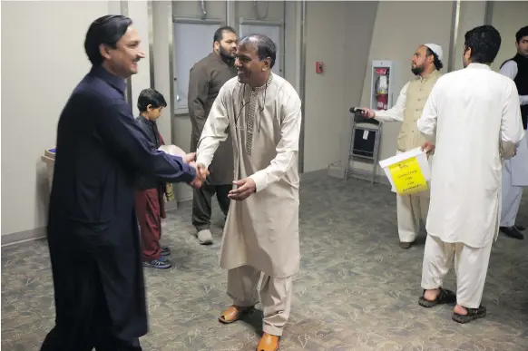  ?? MATT OLSON ?? Yousuf Mohammad, right, greets people as they enter the hall at Prairielan­d Park to celebrate Eid al-adha on Wednesday. Eid officially runs until Saturday.