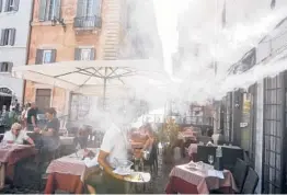  ?? RICCARDO DE LUCA/AP ?? A fan sprays mist as customers sit outside a cafe during a heat wave July 31 in downtown Rome. The temperatur­e that day reached 104 degrees.