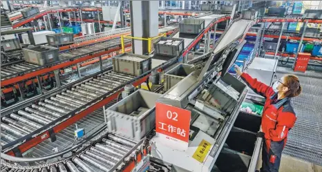  ?? KEVIN FRAYER / GETTY IMAGES ?? A staff member of Chinese e-commerce company JD works on an automated sorting machine at the company’s main logistics hub in Beijing on Nov 11.