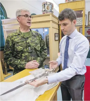  ?? DARREN STONE, TIMES COLONIST ?? Sgt. Dan MacKenzie holds Private Reginald Johnston’s bayonet as Lt. Col. Stephen Sawyer looks on at the Bay Street Armoury on Wednesday.