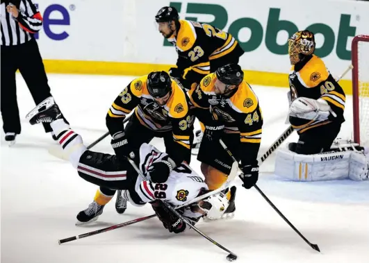  ?? JIM ROGASH/ GETTY IMAGES ?? Boston Bruins defenceman Zdeno Chara checks Bryan Bickell of the Chicago Blackhawks to the ice late in Game 3 of the Stanley Cup Final on Monday as Chara’s defence partner Dennis Seidenberg looks on.